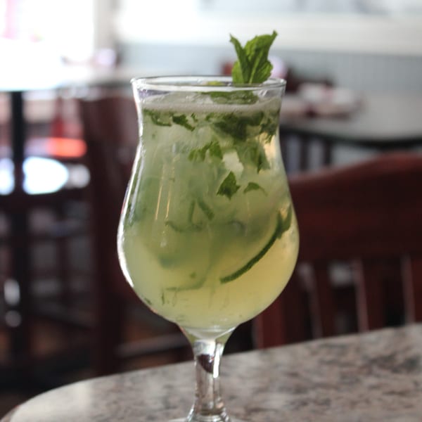 A refreshing mojito cocktail with mint leaves and lime, served in a stemmed glass on a marble table.