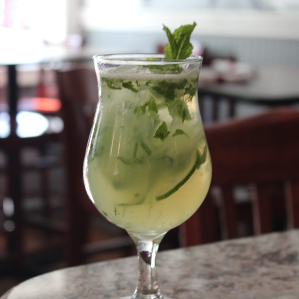 A refreshing mojito cocktail with mint leaves and lime, served in a stemmed glass on a marble table.