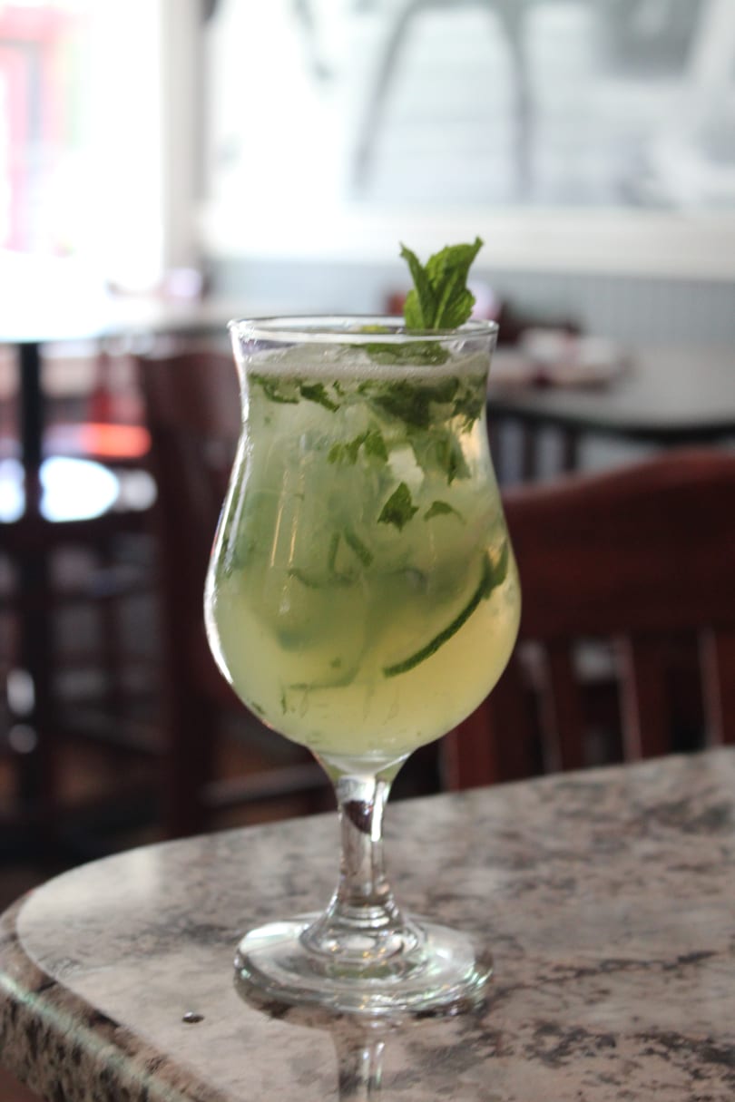 A refreshing mojito cocktail with mint and lime, served in a tall glass on a marble table.